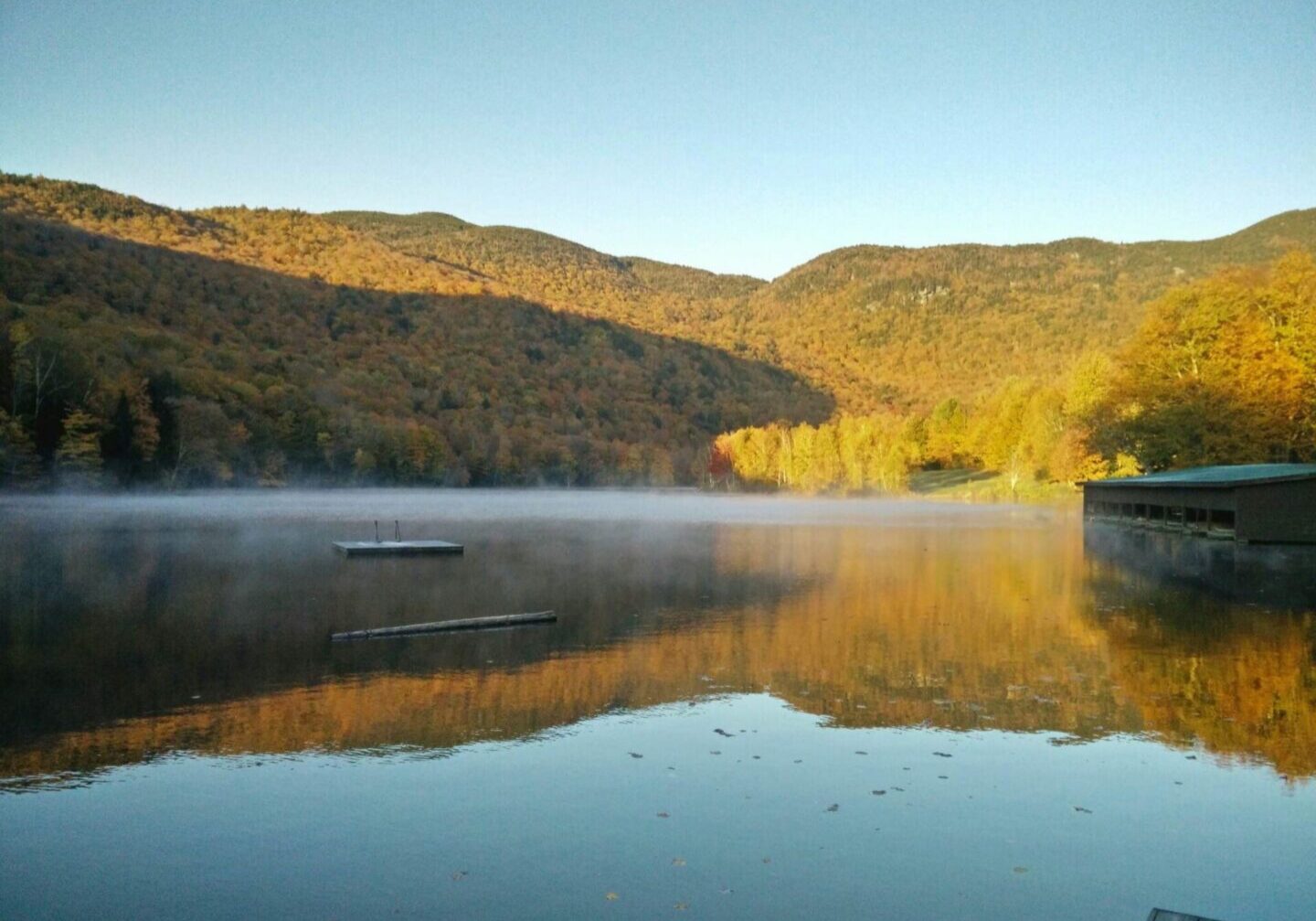 A lake with mountains in the background and trees on one side.